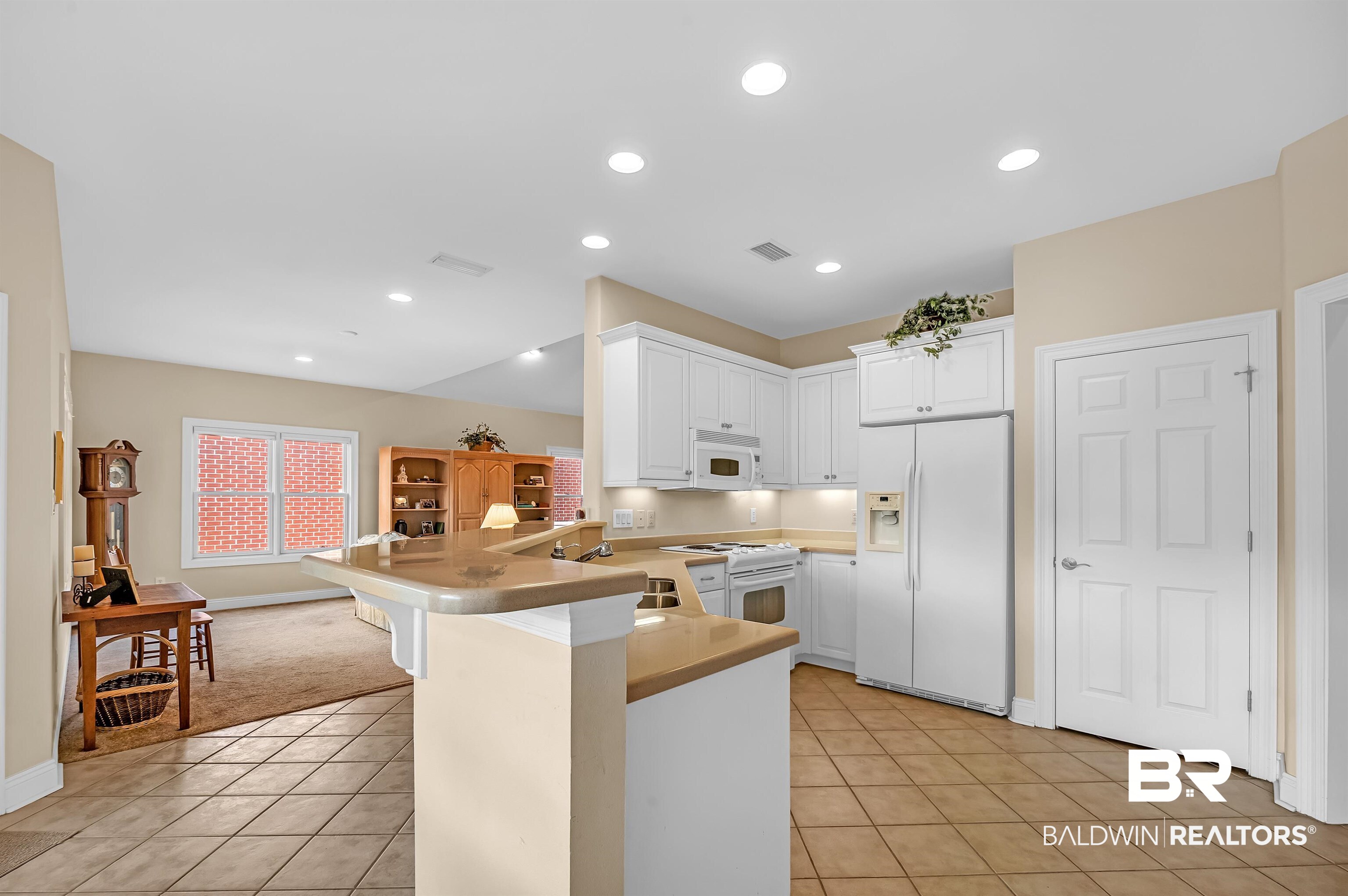 22739 Inverness Way Foley, AL 36535 - Photo 40 of 80 Kitchen featuring white appliances, a peninsula, light tile patterned floors, white cabinets, and light countertops