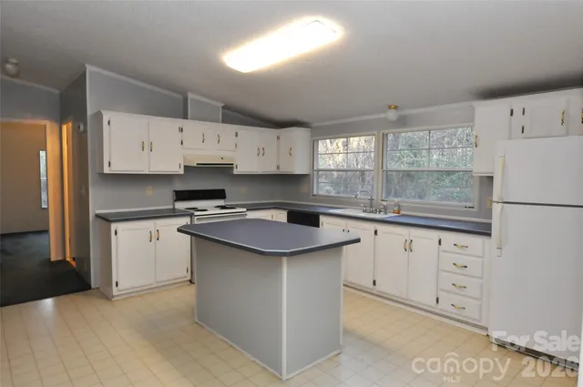 a kitchen with granite countertop white cabinets white stainless steel appliances and sink