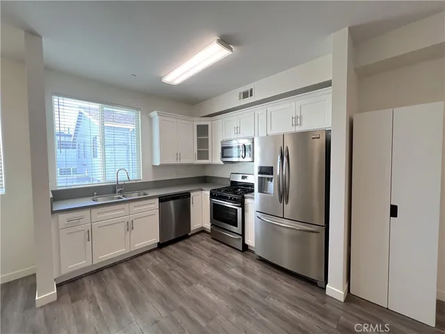 a kitchen with granite countertop stainless steel appliances a refrigerator a sink and cabinets