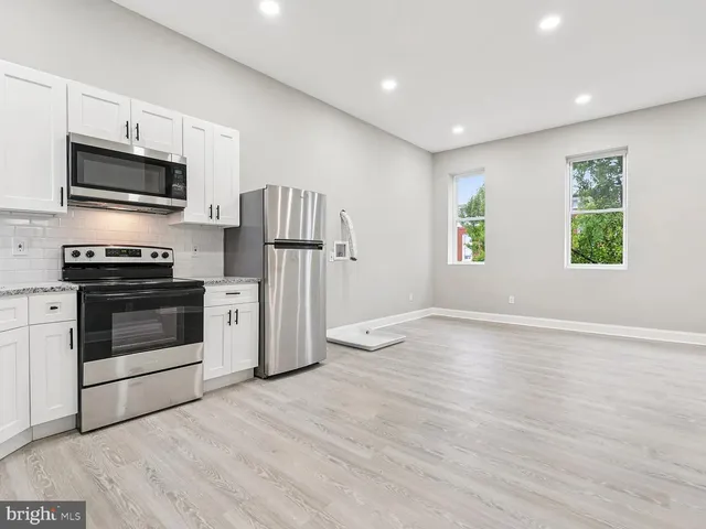 a kitchen with stainless steel appliances a stove top oven a refrigerator cabinets and a window