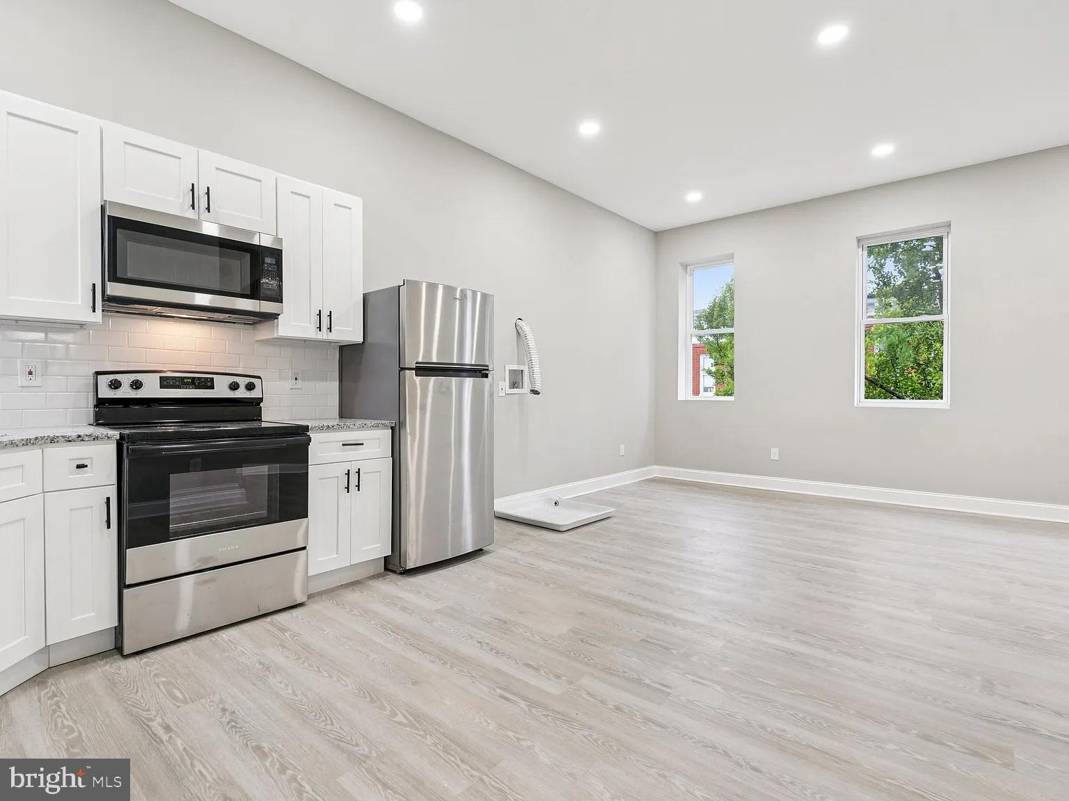 916 North Arlington Avenue, Unit 3 Baltimore, MD 21217 - Photo 1 of 7 a kitchen with stainless steel appliances a stove top oven a refrigerator cabinets and a window