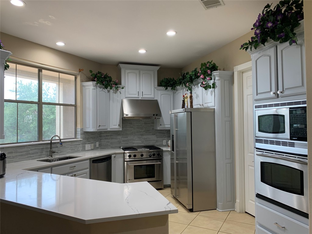 4325 Lago Viento Austin, TX 78734 - Photo 11 of 39 a kitchen with stainless steel appliances kitchen island granite countertop a stove sink and refrigerator