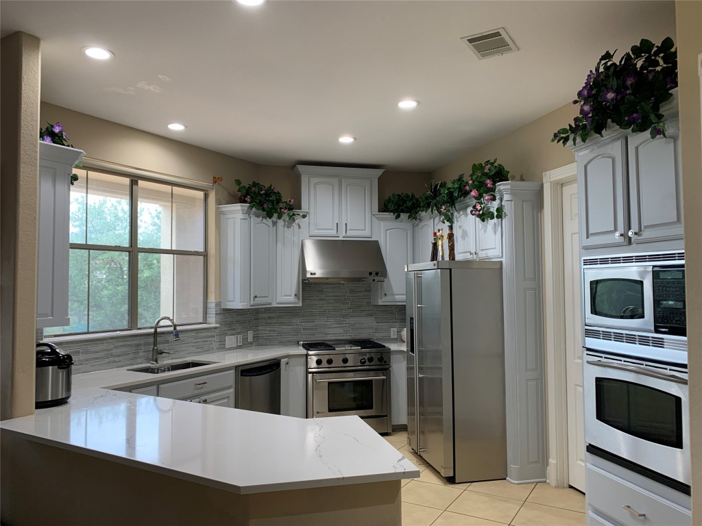 4325 Lago Viento Austin, TX 78734 - Photo 12 of 39 a kitchen with stainless steel appliances a stove a sink a microwave a refrigerator and cabinets