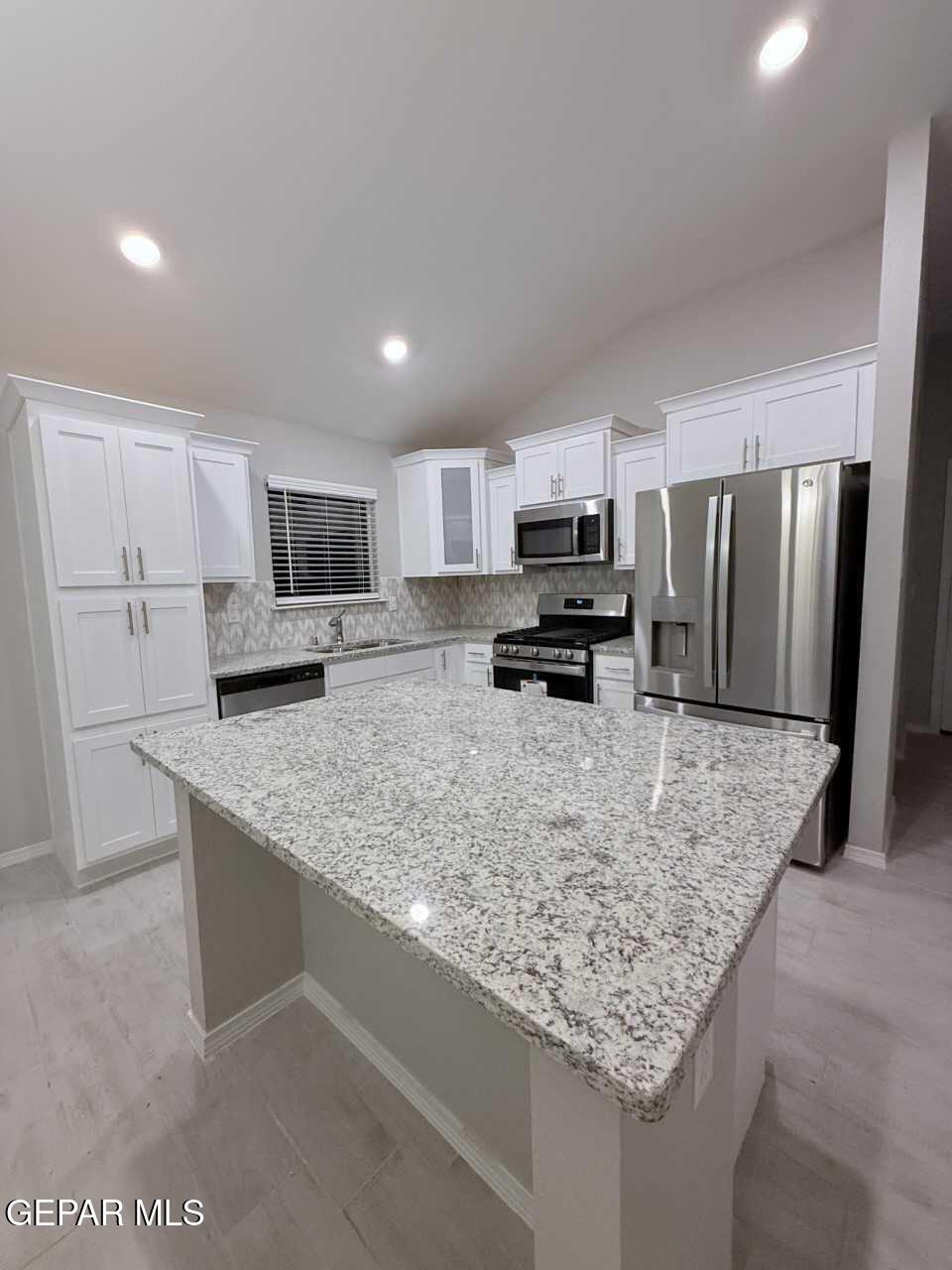12409 Caddo Lane Clint, TX 79836 - Photo 11 of 13 a kitchen with kitchen island granite countertop a sink refrigerator and microwave