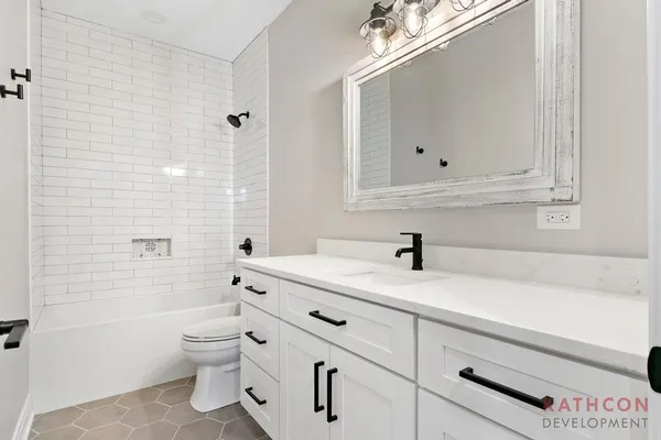 a bathroom with a sink vanity granite toilet and a mirror