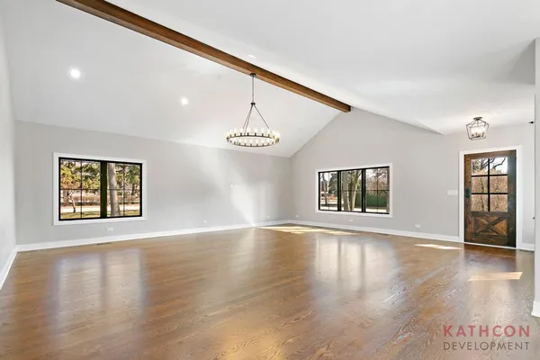 a view of an empty room with window and wooden floor