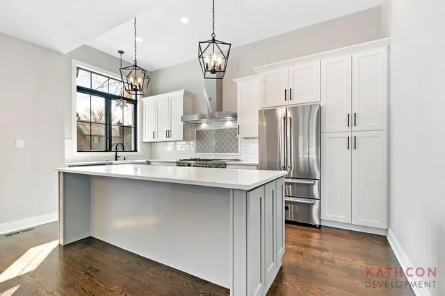 a kitchen with stainless steel appliances granite countertop a sink a refrigerator and a wooden floor