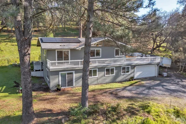 a view of a house with brick walls plants and large tree