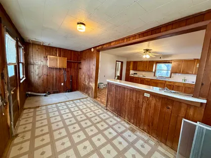 a view of a livingroom with wooden floor and a kitchen