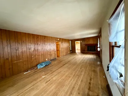an empty room with windows and fireplace