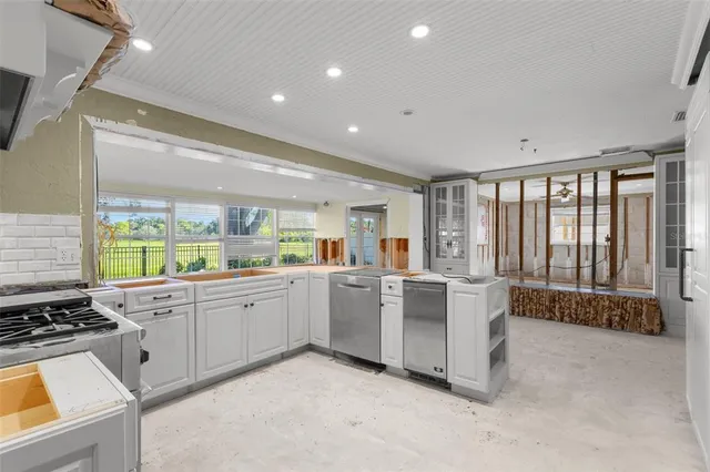 a open kitchen with white cabinets stove and sink