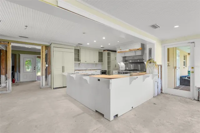 a large white kitchen with stainless steel appliances granite countertop a large counter top and a stove top oven