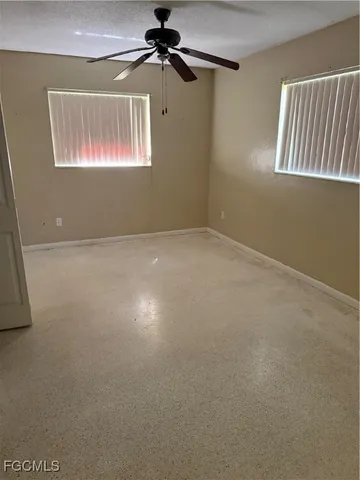 an empty room with windows and fan