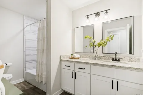a bathroom with a granite countertop sink a toilet and a mirror