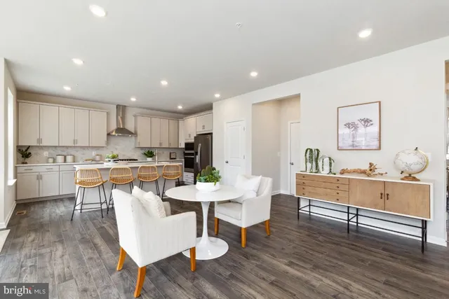 a living room with furniture and kitchen view with wooden floor