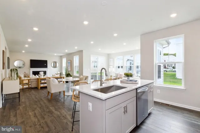 a living room with stainless steel appliances kitchen island granite countertop a sink and dishwasher with wooden floor