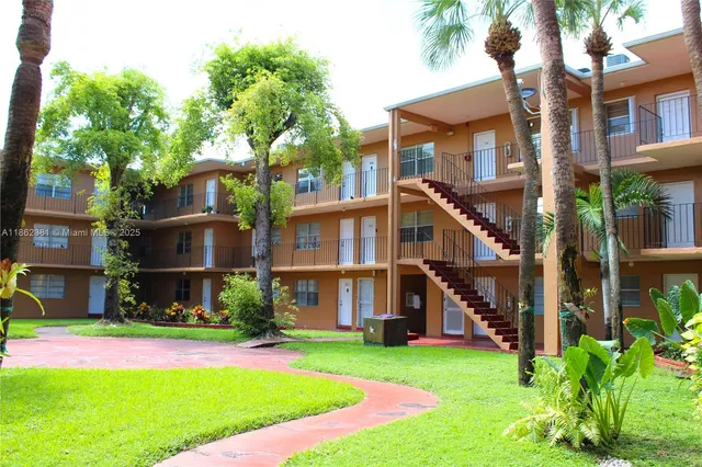 a view of a brick house with a yard and plants