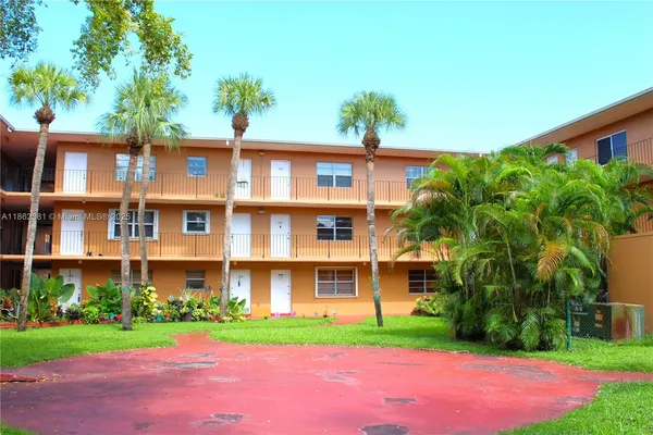 a front view of a multi story residential apartment building with yard and green space