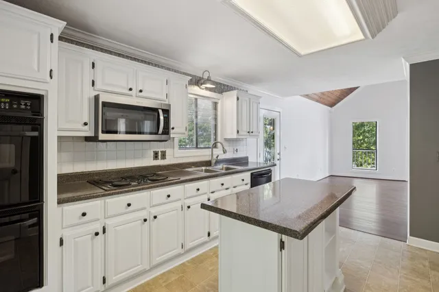 a kitchen with granite countertop a sink white cabinets and stainless steel appliances