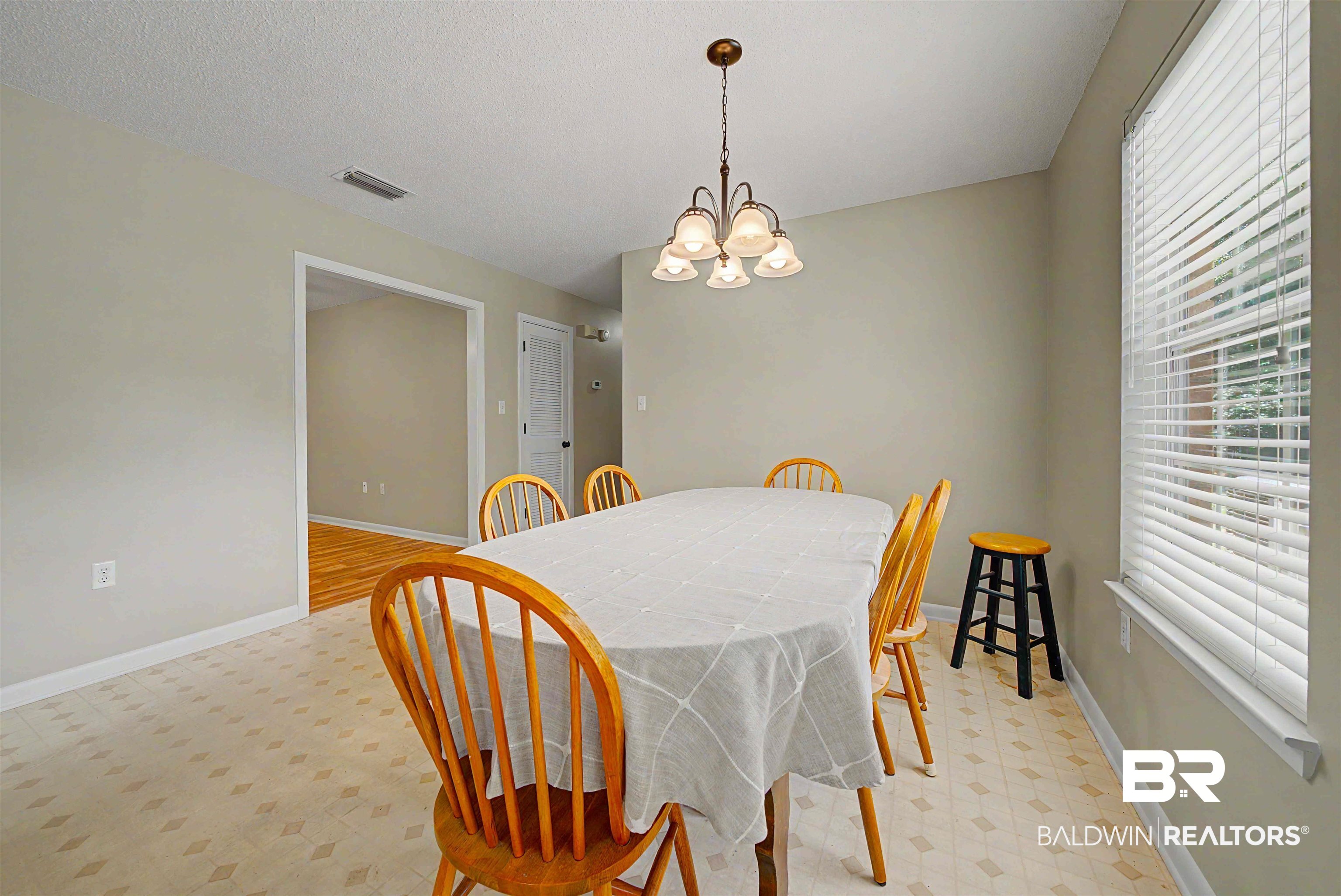 22963 Highway 98 Foley, AL 36535 - Photo 13 of 52 Dining area featuring patterned flooring, neutral wall tones, a multi-light chandelier, and a window with blinds