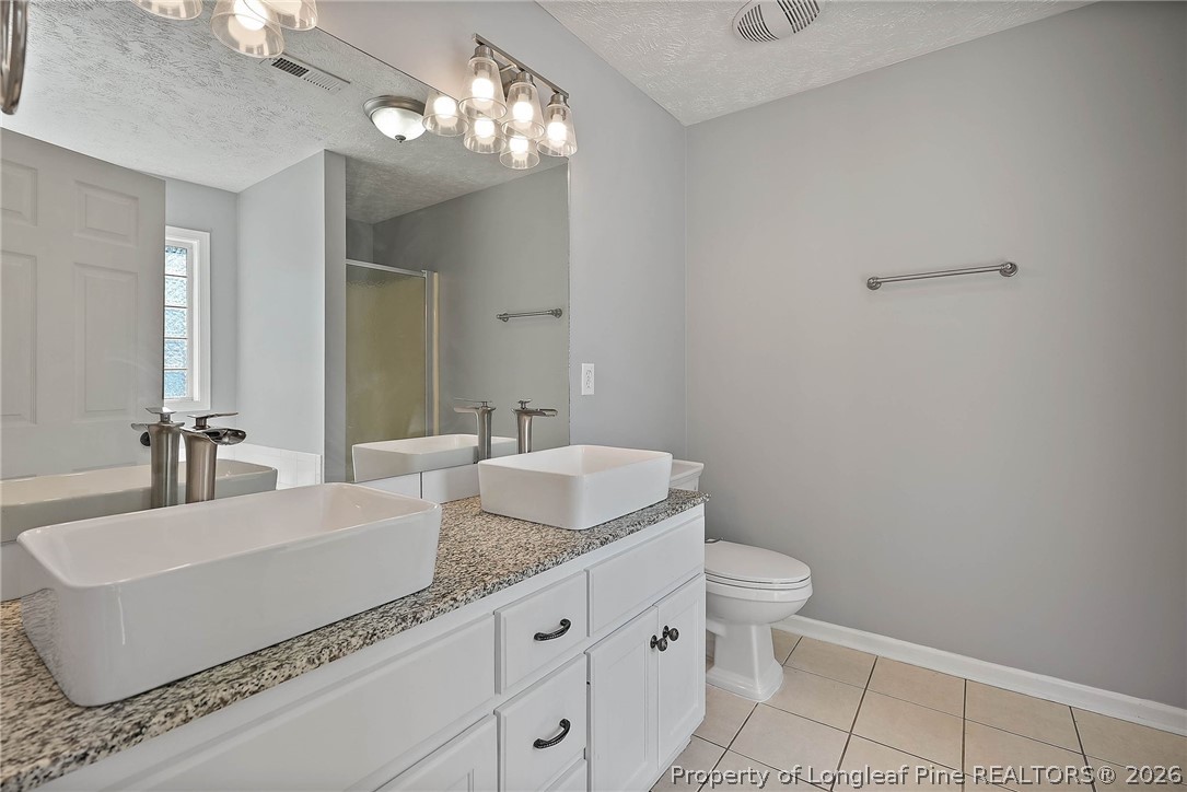 5353 Pringle Way Hope Mills, NC 28348 - Photo 14 of 29 a bathroom with a granite countertop sink a toilet and a mirror