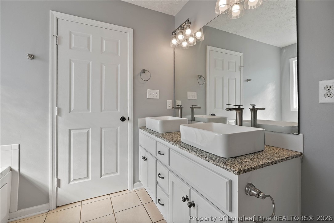 5353 Pringle Way Hope Mills, NC 28348 - Photo 17 of 29 a bathroom with a granite countertop sink a mirror and a vanity