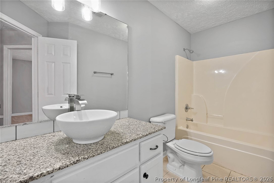 5353 Pringle Way Hope Mills, NC 28348 - Photo 19 of 29 a bathroom with a granite countertop sink toilet mirror and bathtub