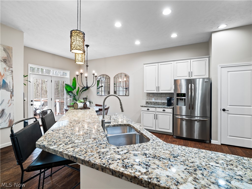 8898 Harvest Ridge Way North Ridgeville, OH 44039 - Photo 8 of 41 Kitchen with light stone counters, stainless steel fridge, white cabinets, a chandelier, and backsplash