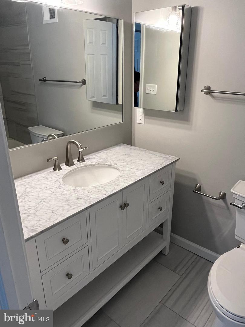 355 Crescendo Way Silver Spring, MD 20901 - Photo 8 of 23 a bathroom with a granite countertop sink a toilet and mirror