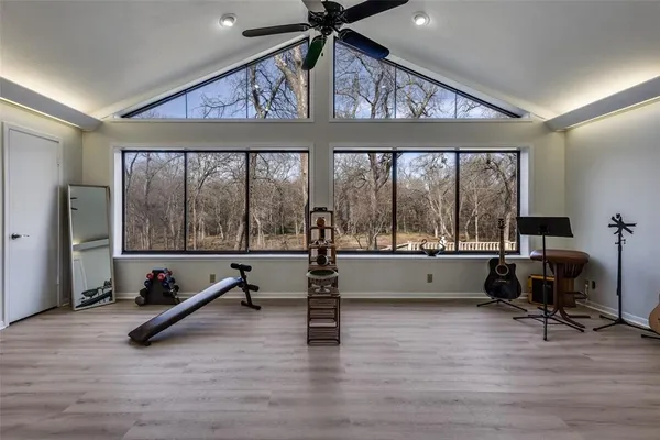 a view of an empty room with wooden floor and windows
