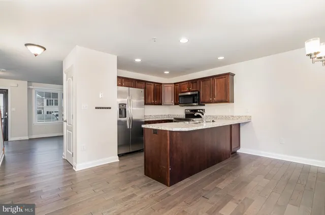 a kitchen with stainless steel appliances granite countertop a stove a refrigerator a sink and a oven with wooden floor