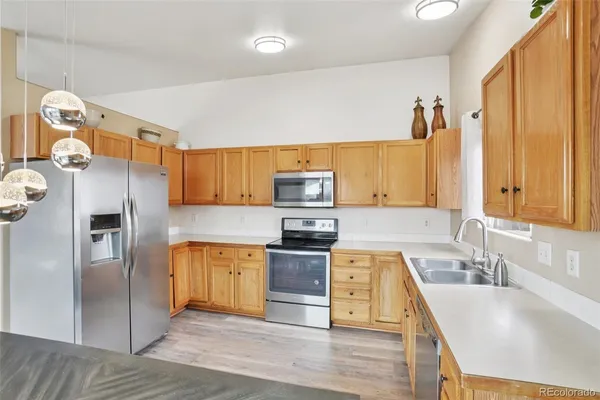 a kitchen with stainless steel appliances granite countertop a refrigerator a stove and a sink with wooden floors