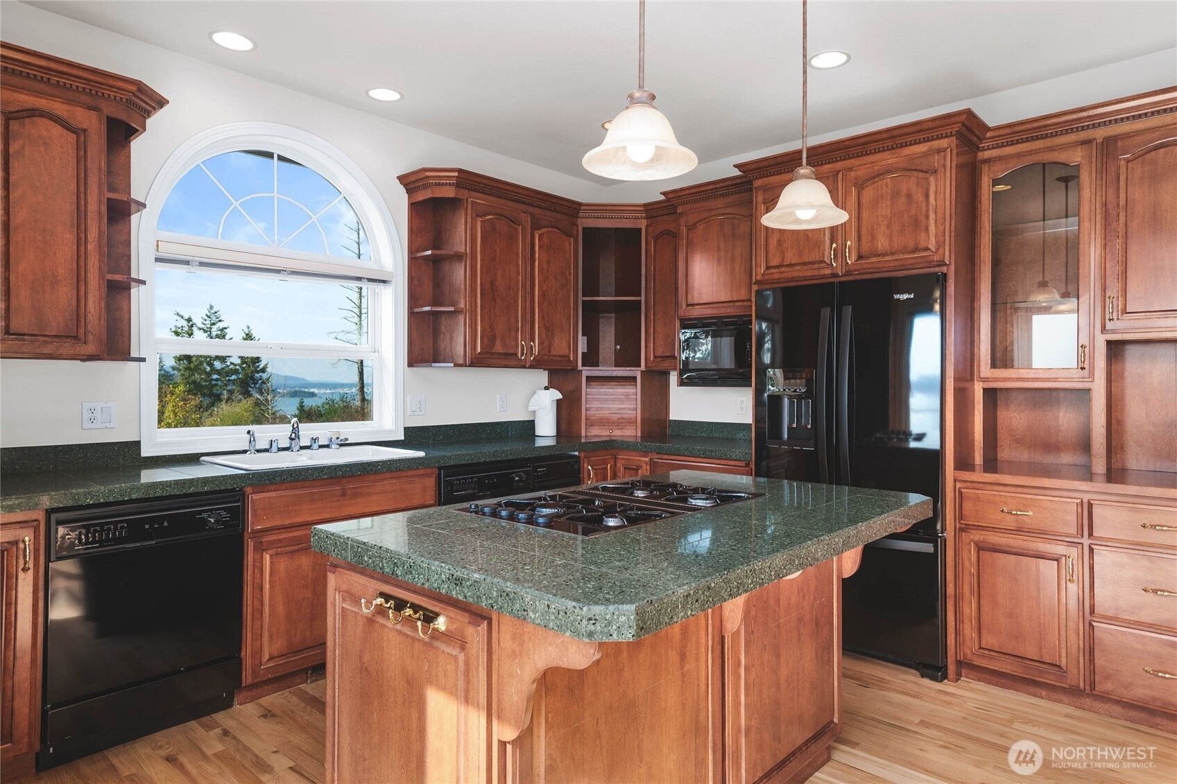 8661 Southridge Place Anacortes, WA 98221 - Photo 9 of 39 a kitchen with kitchen island granite countertop a stove a sink a refrigerator and a wooden cabinets
