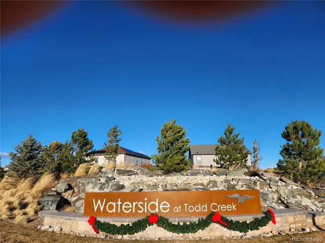 a view of a sign board with buildings in the background