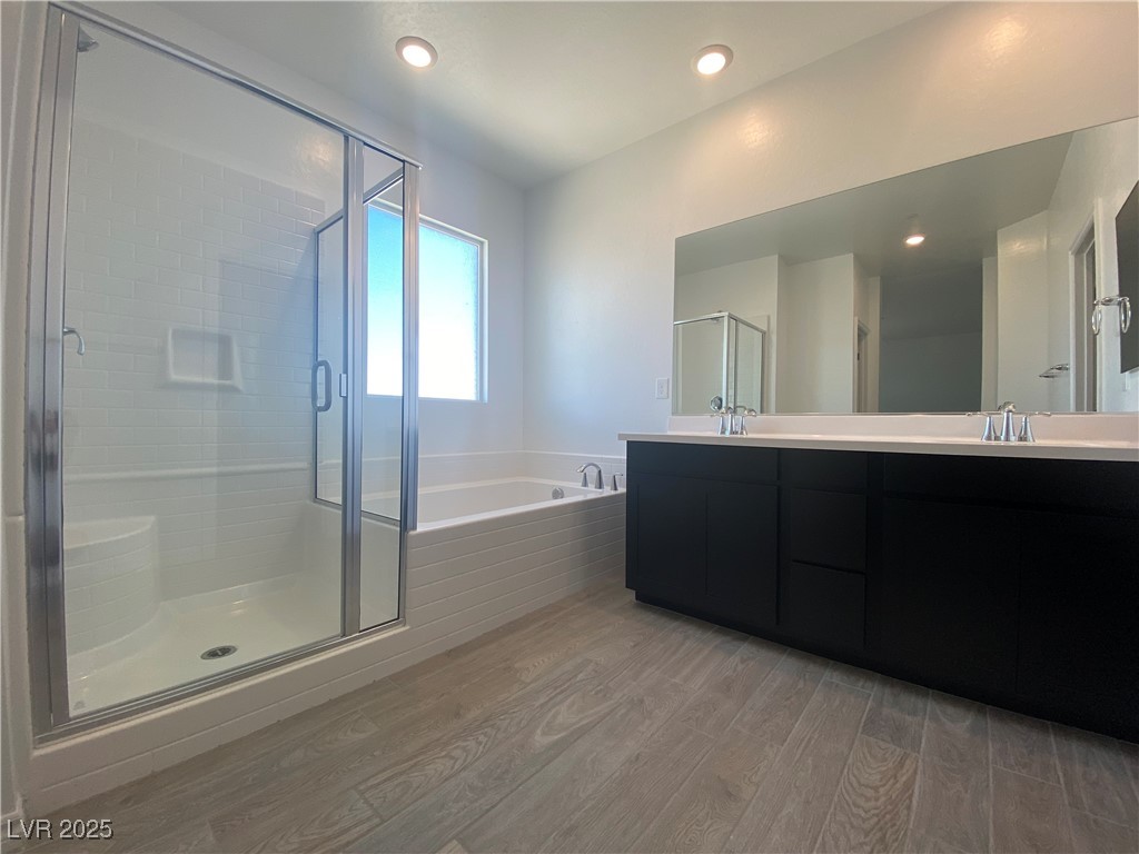 8846 Sasquatch Run Avenue Las Vegas, NV 89166 - Photo 19 of 21 Full bathroom with a bath, light wood-type flooring, double vanity, a shower stall, and recessed lighting