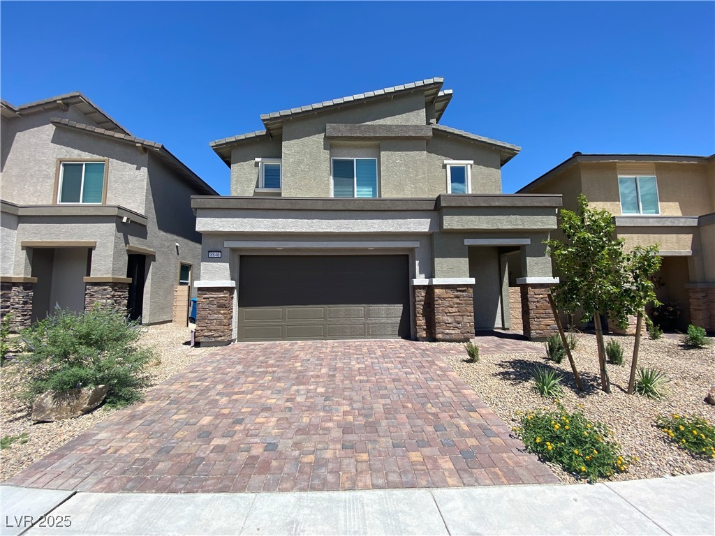 8846 Sasquatch Run Avenue Las Vegas, NV 89166 - Photo 2 of 21 Prairie-style house with stone siding, stucco siding, decorative driveway, and a garage