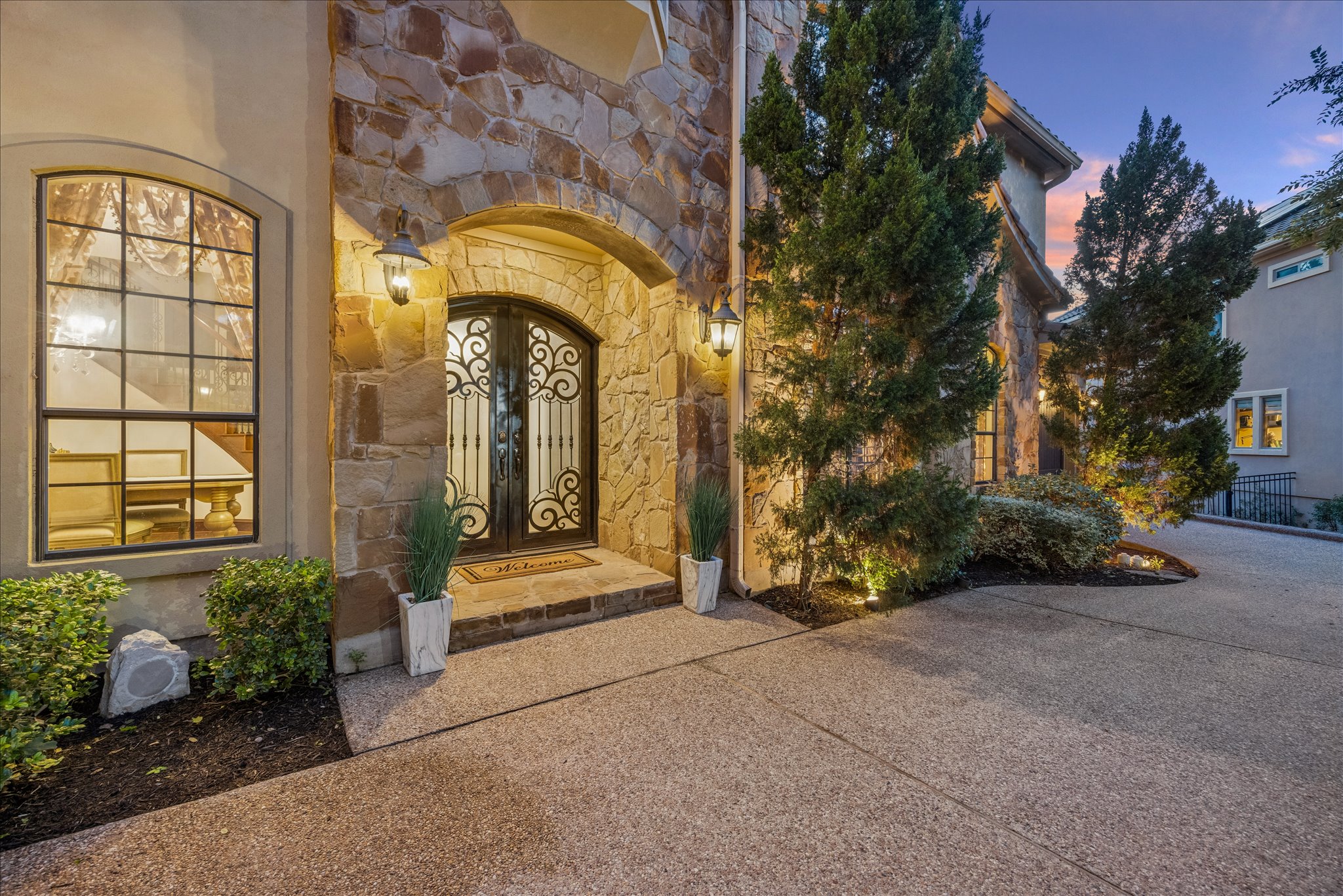 11805 Ranchview Court Austin, TX 78732 - Photo 4 of 36 Stone veneer facade featuring an arched entry with wrought iron double doors, complemented by two exterior wall sconces