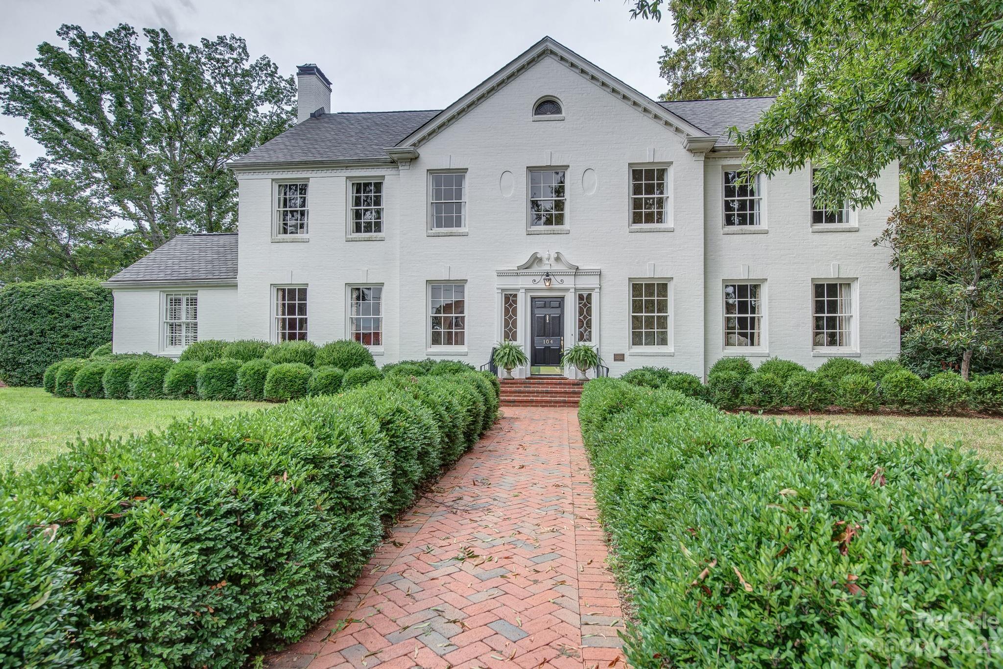 a view of a white house with a yard and potted plants