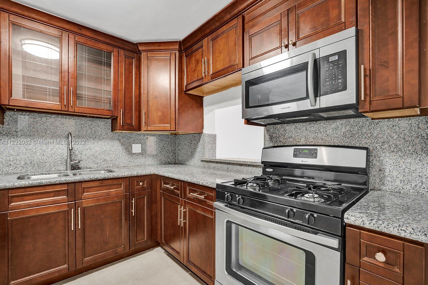 6904 North Kendall Drive, Unit F102 Pinecrest, FL 33156 - Photo 7 of 19 a kitchen with stainless steel appliances granite countertop a stove microwave and sink