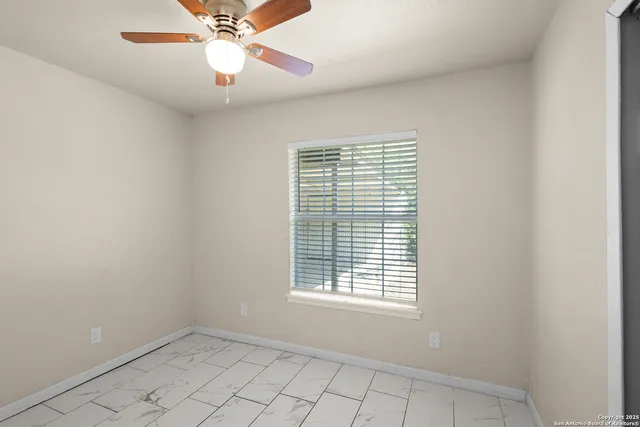 a view of an empty room with window and chandelier fan