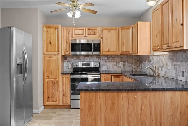 a kitchen with stainless steel appliances granite countertop a refrigerator a stove top oven a sink and dishwasher
