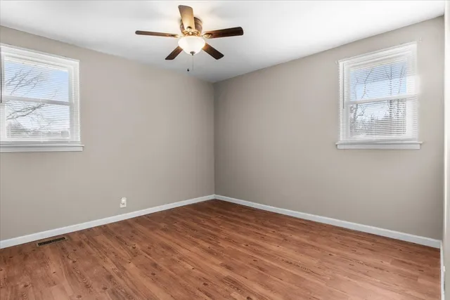 a view of empty room with wooden floor and fan