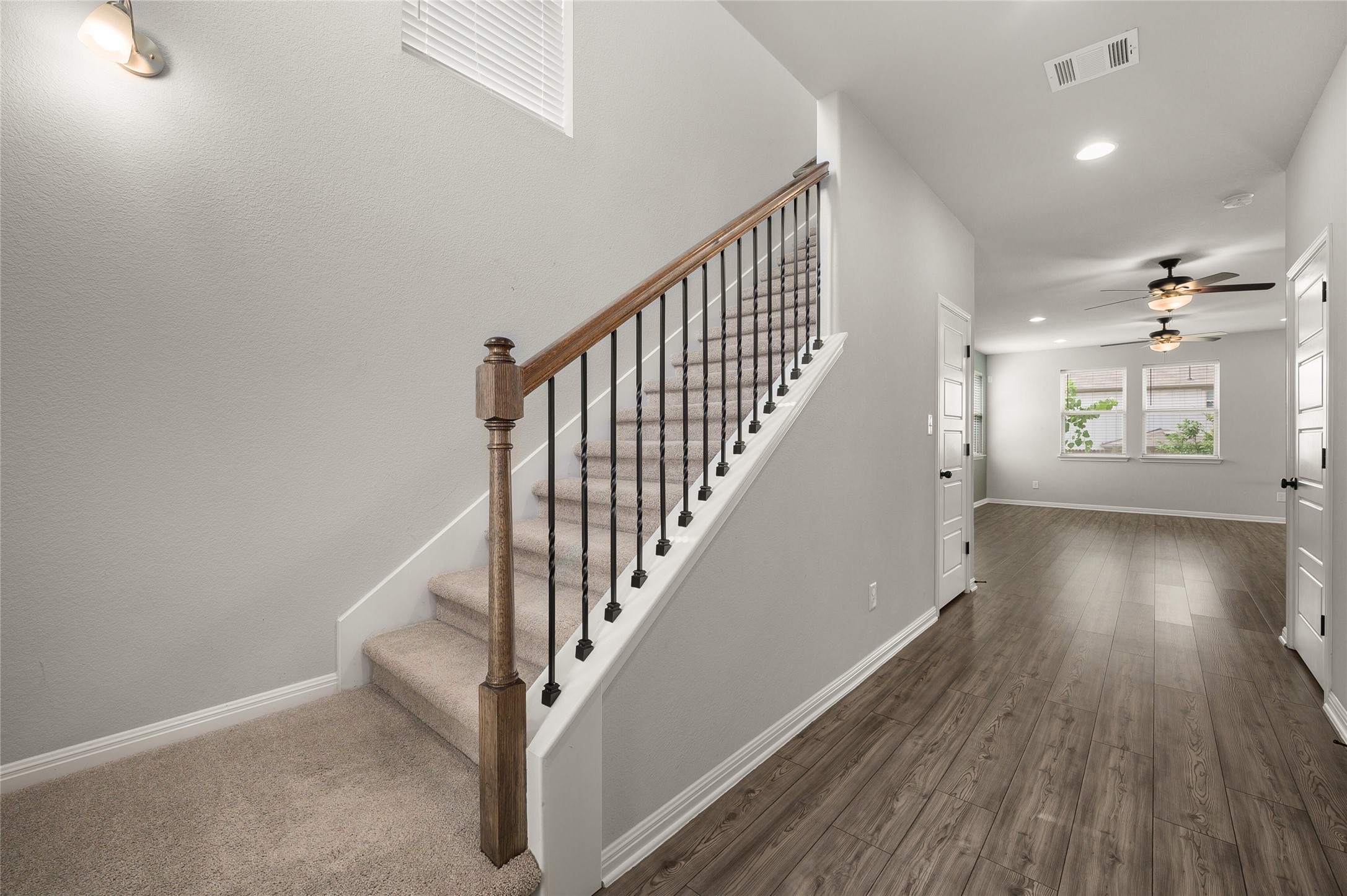 101 Lambert Street Leander, TX 78641 - Photo 4 of 33 A striking stairway with wrought iron balusters leads to an upper level, complementing the warm wood flooring throughout.