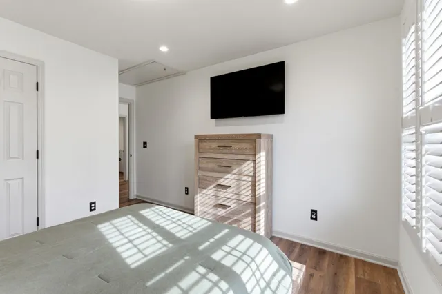 a view of bedroom with wooden floor and flat screen tv