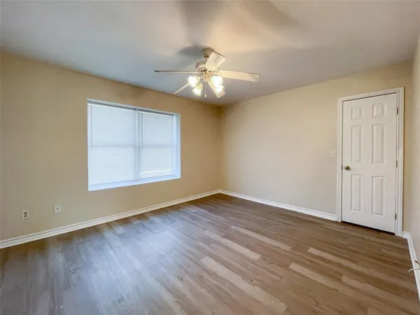 an empty room with wooden floor chandelier fan and windows