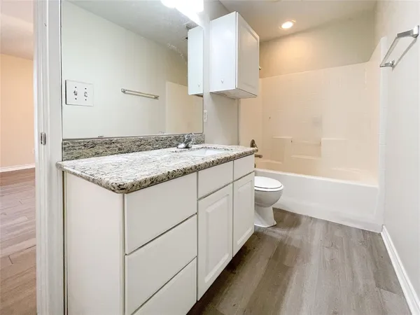 a bathroom with a granite countertop sink a toilet and shower