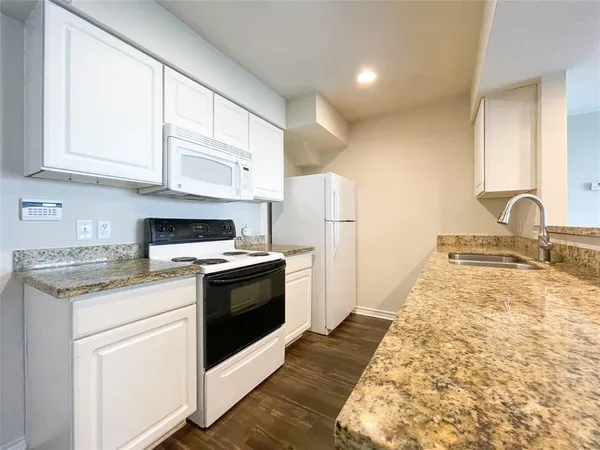 a kitchen with granite countertop white cabinets and white appliances