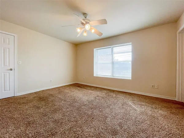 an empty room with wooden floor chandelier fan and windows