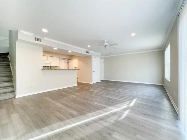 an empty room with wooden floor and kitchen view