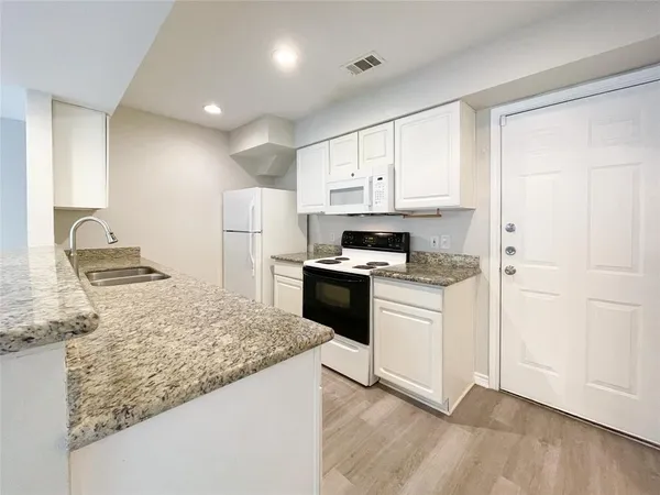 a kitchen with granite countertop white cabinets and white appliances
